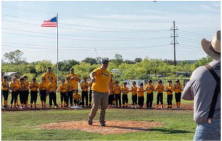 TAKE ME OUT TO THE BALLGAME- Amongst the gathering of Menard Youth Baseball &amp; Softball players on the field Saturday, organization volunteer and coach Cooper Tipton threw out the opening pitch for the 2024 season. Teams ranging from 3-14 years will have games both in Menard and across the area, including Mason, Junction, llano and more. Pictured right, catching for the first pitch, is MYB volunteer and coach Lewis “Cedarberry” Baker. Nora Davis, photo.