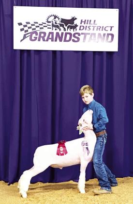 RED LOOKS GOOD ON YOU- Kade Bannowsky shows off his second place ribbon with his medium-weight Finewool lamb at the Hill District Grandstand Show held in Llano this week. Bannowsky was Menard's highest-placing lamb exhibitor. Courtesy photo.