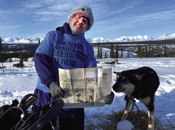 Dora Wright and sled dog Oryx enjoying The Menard News while mushing in Alaska earlier in the year. Oryx ran in the wheel position next to Dora’s sled and loved sleeping in Dora’s sled at night. As an added bonus, Dora not only took The Weekly Miracle on her Alaska trip, she also sported a London Hall shirt over her cold weather gear; it’s safe to say the Menard/Kimble County area was well represented in Alaska. Courtesy Photo.