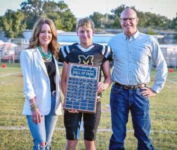 2025 MHS HALL OF FAME INDUCTEES- Suzanne Hofmann Erickson (Class of '88) and John Hofmann (Class of '85) were honored prior to last Friday's football game in Menard. MHS Student Council representative Kade Bannowsky, center, presented the plaque. Courtesy photo.