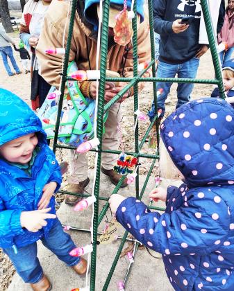 EARLY HEAD START students Colter Bragdon and Havana Childs delight in taking their chance to place ornaments on the class tree provided in the city’s festive light display at low water park. Courtesy photo.