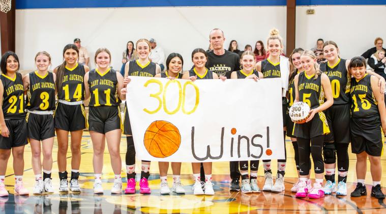 LEFT: THREE HUNDRED STRONG- Last Tuesday's 64-18 Lady Jacket victory over Rochelle marked three-hundred career wins for third-year Menard girls head coach Grant Gooch, pictured center. Of the milestone Gooch commented, 'If that means anything, it's that I've been blessed to coach a great many dedicated and thoughtful athletes.' Gooch and his Lady Js look to add win number 301 when they makeup the Lohn game this Saturday at 11 a.m. in Lohn. Nora Davis, photo.