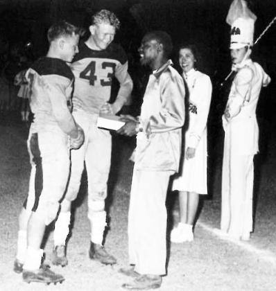 According to a Facebook post on Menard County, Texas - History and Geneology (MCTHG), this photograph appeared in the 1951 Yellowjacket Annual. In the photo, Jug Shannon, center, receives a football jacket for his work as the team trainer. With Jug are the teams co-captains Dick Ellis and Gerald Crisp. The Drum Major pictured right has been identified as Charles Freeman. Photo courtesy MCTHG Facebook page.