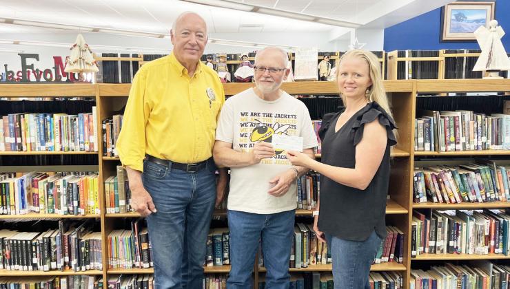Below, Menard Library Club treasurer Kathy Mews, pictured right, recently presented Randy Corbin and Pastor David Medley with a $1,000 library donation to the Mission Team for ongoing local flood relief and repairs.