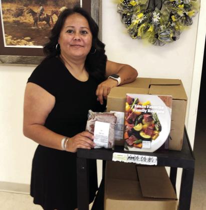 Menard County Community Center director Odie Zamora shows the beef and recipe books recently donated to Menard by the Hill County CattleWomen. Courtesy photo.
