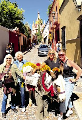 The lovely ladies, (L-R) Vicki Davis Olson, Linda Ray Myers, Susan Porter Miller and Caroline Starry, posed with a burro on Aldama Steet while the Parroquia de San Miguel Archange was visible in the background. Courtesy photo.