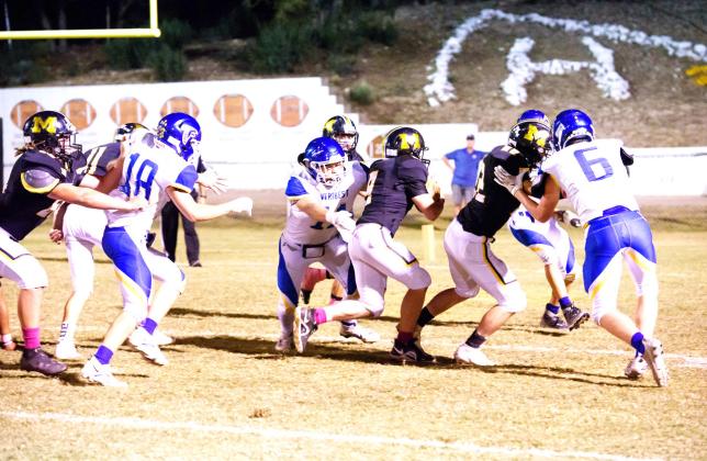 FINDING HIS WAY- Junior Hunter Whitaker, center, finds a hole and rushes in for a Menard touchdown against Veribest last Friday night. William Doyle blocks to the right, and Kade Rayburn helps out to his left. Brandon Spinks and Wyatt Terrell keep defenders at bay from the back side. Nora Davis, photo.