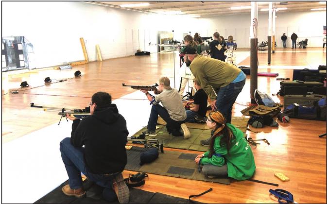 SHARP SHOOTERS - Heart of Texas Indoor Match: (L-R) Menard 4-H Rifl es Larkin Loeffler, Mia Estrada, and Wesley Compton show top form in the kneeling position while John Compton coaches his son. Benjamin Burch is at John’s right. Courtesy photo.