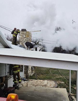 Menard VFD's Beau Tipton and Tyler Wagner (on roof) and Skeet Rogers (on the ground) respond to a chimney fire on Sunday. Photo by MVFD.