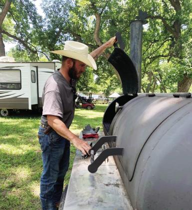 LEFT- Jayme Mayfield checks the progress inside his pit during Saturday's Jim Bowie Day Cook-off. Results will be in next week's edition.