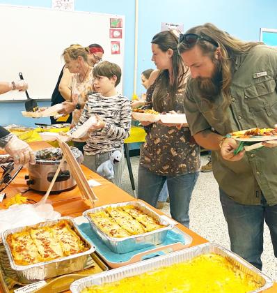 ABOVE- Taste of Menard diners check out the goods as they fill their plates at the Boys &amp; Girls Club's annual potluck fundraiser. Courtesy photo.