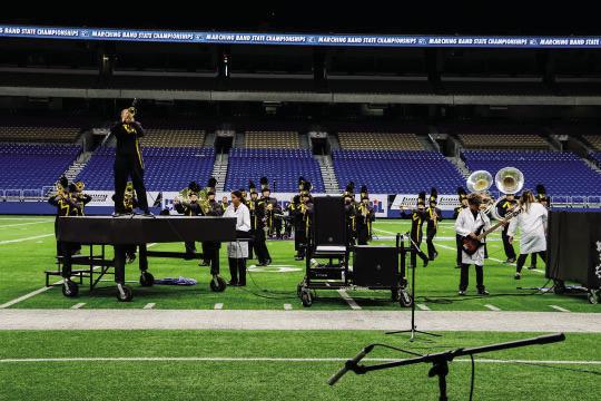 Soloist Kailey Morris performs atop the piano prop, while Lauren Guerrero plays the keyboard and Ian Brown plays guitar in their state performance.