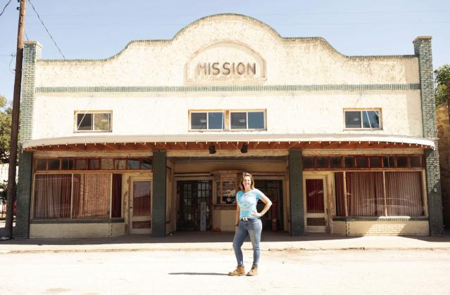 ABOVE- New Mission Theatre owner Lisa Lewis poses in front of her recent purchase, the Menard Mission Theatre, located at 220 Bevans Street. Photo courtesy L. Lewis.