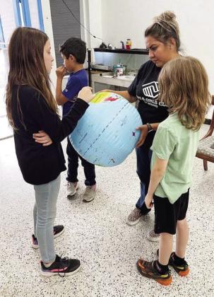Club employee Laressa Brown, center, helps Club members scour the globe during the 'Globe Game' activity in early November. In addition to educational programs, Menard's B&amp;G Club offers members homework help, healthy meal and snack options, and an overall safe place to be. Pictured left to right-Libby Teague, Ian Brown, Barrett Thigpen. Courtesy photo.