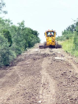ABOVE- A visiting TXDOT machine and operator works to make Garvin Ln. passable after the July 4 floods. TMN photo.