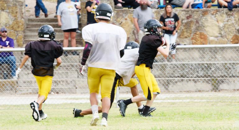 I’LL TAKE THAT- Menard’s Bryce Davis, far right, slips away with an interception during the Yellowjackets’ football scrimmage in Rochelle last week. The team faces Hill Country Christian at home on Thursday, August 25 in their first offocoal game as a six-man team. TMN photo.