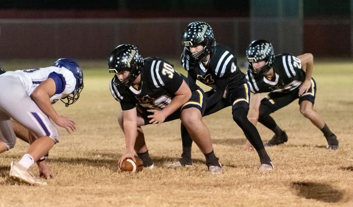 BI-DISTRICT BLOWOUT- Senior Tate Wagner, junior Eli Weatherly, and senior Bryce Davis line up prior to a snap last Friday against Knippa in Rocksprings. The Jackets mercy-ruled the Rockcrushers 62-0 by the half. Playoff week 2 sees Menard face Gordon, the reigning state champion of Class A, Div. 1. See area round playoff info below or on page 8. Nora Davis, photo.