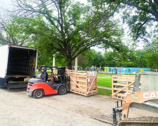 Crates of playground equipment being unloading by a forklift. 