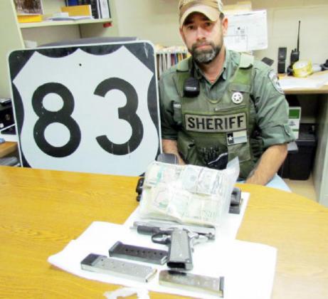 SEIZURE SELECTION- Deputy Michael Smith with the handgun, drugs, and cash seized during the traffic stop of a Colorado man last week. Photo courtesy MCSO.