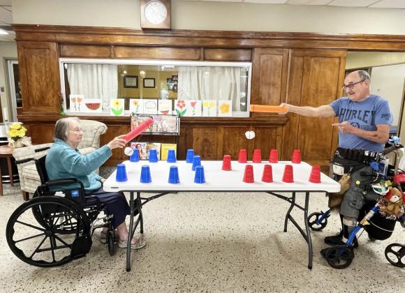 LEFT- There will always be something fun and stimulating going on for the residents of Menard Manor Skilled Nursing Facility if Activities Director Cheryl Spoons has anything to do with it, and she does! Pictured is Nellie Frnka and David Garza taking part in an activity using a “snowball” tied to a piece of pool noodle to work on hand-eye coordination by knocking down Solo cups. Manor residents enjoy a variety of games, activities, crafts and interaction year-round. Courtesy photo.