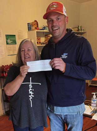 GIVING BACK- Darla Pollard, with the Hope House food pantry, accepts an annual donation of $500 from Menard Farm Bureau Board President Tyson Roll. Courtesy Photo.