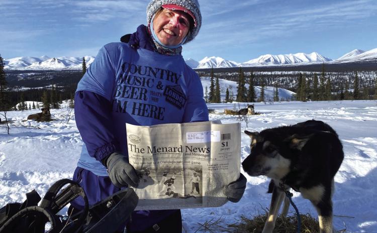 Dora Wright and sled dog Oryx enjoying The Menard News while mushing in Alaska earlier in the year. Oryx ran in the wheel position next to Dora’s sled and loved sleeping in Dora’s sled at night. As an added bonus, Dora not only took The Weekly Miracle on her Alaska trip, she also sported a London Hall shirt over her cold weather gear; it’s safe to say the Menard/Kimble County area was well represented in Alaska. Courtesy Photo.