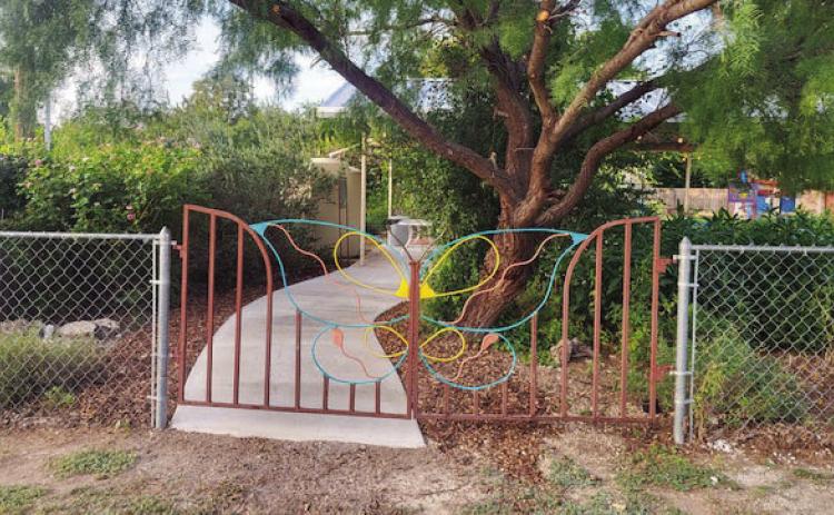 THE DECORATIVE metal gate on the northeast side of the Marjorie Russell Education Garden is now complimented by the addition of a cement walkway to the pavilion. Courtesy photo.