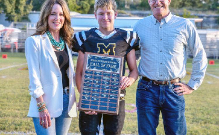 2025 MHS HALL OF FAME INDUCTEES- Suzanne Hofmann Erickson (Class of '88) and John Hofmann (Class of '85) were honored prior to last Friday's football game in Menard. MHS Student Council representative Kade Bannowsky, center, presented the plaque. Courtesy photo.