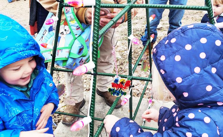 EARLY HEAD START students Colter Bragdon and Havana Childs delight in taking their chance to place ornaments on the class tree provided in the city’s festive light display at low water park. Courtesy photo.