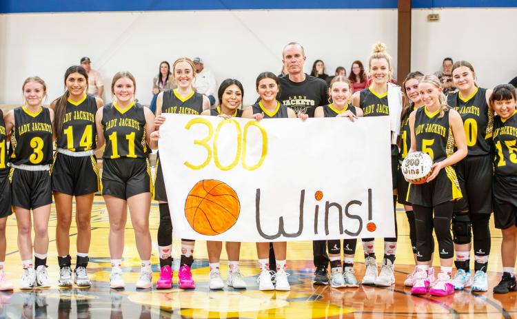 LEFT: THREE HUNDRED STRONG- Last Tuesday's 64-18 Lady Jacket victory over Rochelle marked three-hundred career wins for third-year Menard girls head coach Grant Gooch, pictured center. Of the milestone Gooch commented, 'If that means anything, it's that I've been blessed to coach a great many dedicated and thoughtful athletes.' Gooch and his Lady Js look to add win number 301 when they makeup the Lohn game this Saturday at 11 a.m. in Lohn. Nora Davis, photo.