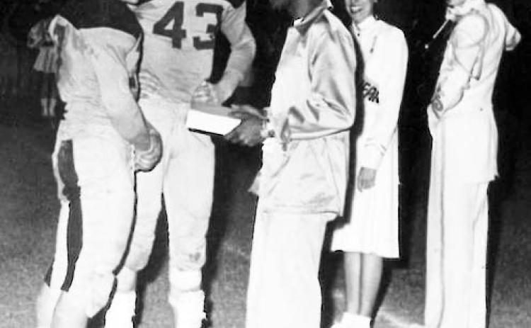 According to a Facebook post on Menard County, Texas - History and Geneology (MCTHG), this photograph appeared in the 1951 Yellowjacket Annual. In the photo, Jug Shannon, center, receives a football jacket for his work as the team trainer. With Jug are the teams co-captains Dick Ellis and Gerald Crisp. The Drum Major pictured right has been identified as Charles Freeman. Photo courtesy MCTHG Facebook page.