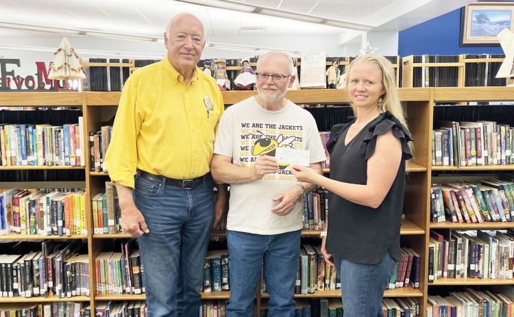 Below, Menard Library Club treasurer Kathy Mews, pictured right, recently presented Randy Corbin and Pastor David Medley with a $1,000 library donation to the Mission Team for ongoing local flood relief and repairs.