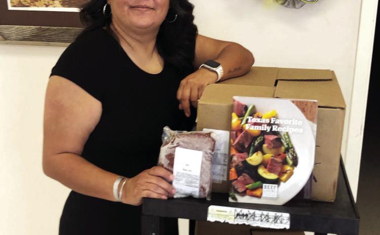 Menard County Community Center director Odie Zamora shows the beef and recipe books recently donated to Menard by the Hill County CattleWomen. Courtesy photo.