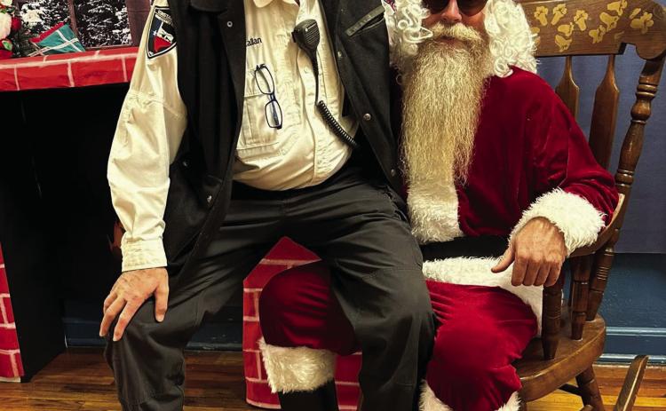 Santa made a very special visit to Menard Elementary School last week, and Resource Officer Constable Callan did not miss a chance to tell the big guy what he wants for Christmas! Courtesy Photo.