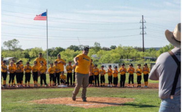 TAKE ME OUT TO THE BALLGAME- Amongst the gathering of Menard Youth Baseball &amp; Softball players on the field Saturday, organization volunteer and coach Cooper Tipton threw out the opening pitch for the 2024 season. Teams ranging from 3-14 years will have games both in Menard and across the area, including Mason, Junction, llano and more. Pictured right, catching for the first pitch, is MYB volunteer and coach Lewis “Cedarberry” Baker. Nora Davis, photo.