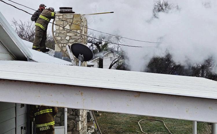Menard VFD's Beau Tipton and Tyler Wagner (on roof) and Skeet Rogers (on the ground) respond to a chimney fire on Sunday. Photo by MVFD.