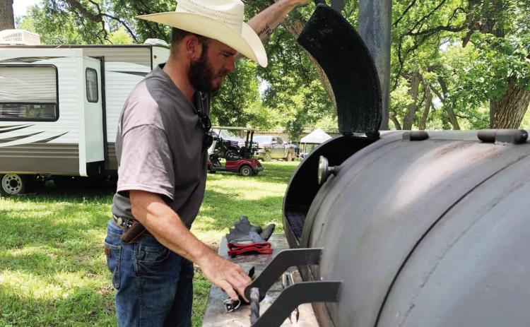 LEFT- Jayme Mayfield checks the progress inside his pit during Saturday's Jim Bowie Day Cook-off. Results will be in next week's edition.