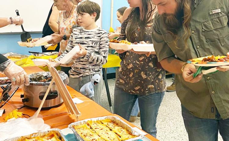 ABOVE- Taste of Menard diners check out the goods as they fill their plates at the Boys &amp; Girls Club's annual potluck fundraiser. Courtesy photo.