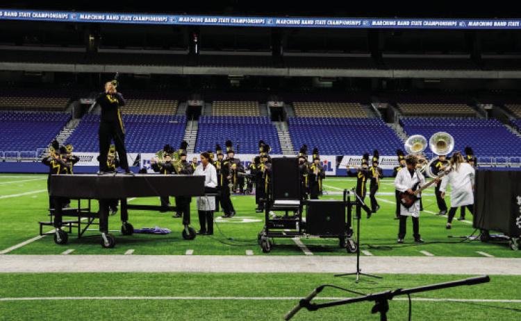 Soloist Kailey Morris performs atop the piano prop, while Lauren Guerrero plays the keyboard and Ian Brown plays guitar in their state performance.