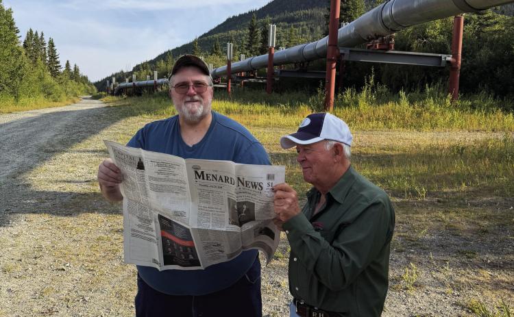 GOOD NEWS TRAVELS- Kelly Miller and Rhome Hill share The Menard News standing under the Trans Alaska Pipeline viewpoint in Copper Center, Alaska. Ginger and Rhome Hill recently traveled to Alaska to Wasilla, Alaska visit dear friends, former Menardians, Kelly and Diane Miller. Kelly is the son of the late Patty (Song of Silver author) and Bobby Miller. Courtesy Photo.