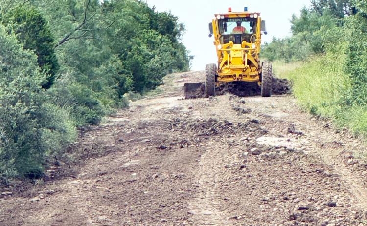 ABOVE- A visiting TXDOT machine and operator works to make Garvin Ln. passable after the July 4 floods. TMN photo.