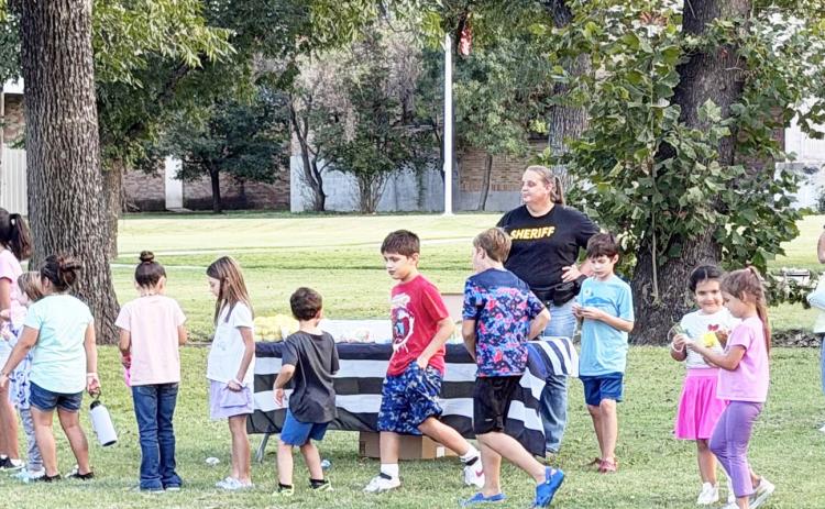RIGHT- MCSO Deputy Dorothy Baker enjoys the beautiful weather Tuesday night at the Menard County National Night Out, held on the courthouse lawn/American Legion Park. The event is annual and nation-wide, and allows local residents a chance to get to know an interact with law enforcement and first responders. Chamber photo.