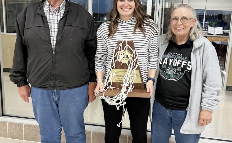 GIRLS BASKETBALL COACH OF THE YEAR Kami Williamson, center, is pictured with her parents John and Nancy Williamson of Menard after a playoff win by Coach K's Class 5A Cedar Park Timberwolves earlier this year. Williamson is a Menard High School graduate who played basketball as a Lady Jacket. She then went on to play for West Texas A&amp;M and ASU before beginning her coaching career. See story on page 3.