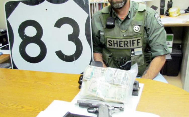 SEIZURE SELECTION- Deputy Michael Smith with the handgun, drugs, and cash seized during the traffic stop of a Colorado man last week. Photo courtesy MCSO.