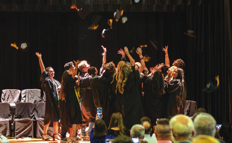 MENARD HIGH SCHOOL’S freshly graduated class takes the traditional cap toss upon the school auditorium stage. Graduations are usually held outdoors at Findlay Field, but the weather had other plans this year. You can read about each graduate in the special graduation feature that will be in next week’s newspaper. The publication was anticipated to be available today, but has since been delayed.